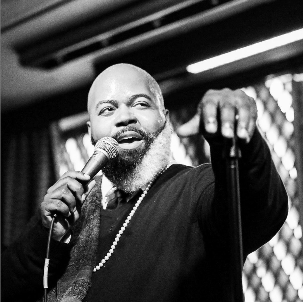 Black and white portrait of C. Anthony Bryant singing on stage with microphone at Ginny's Supper Club in Harlem NYC.